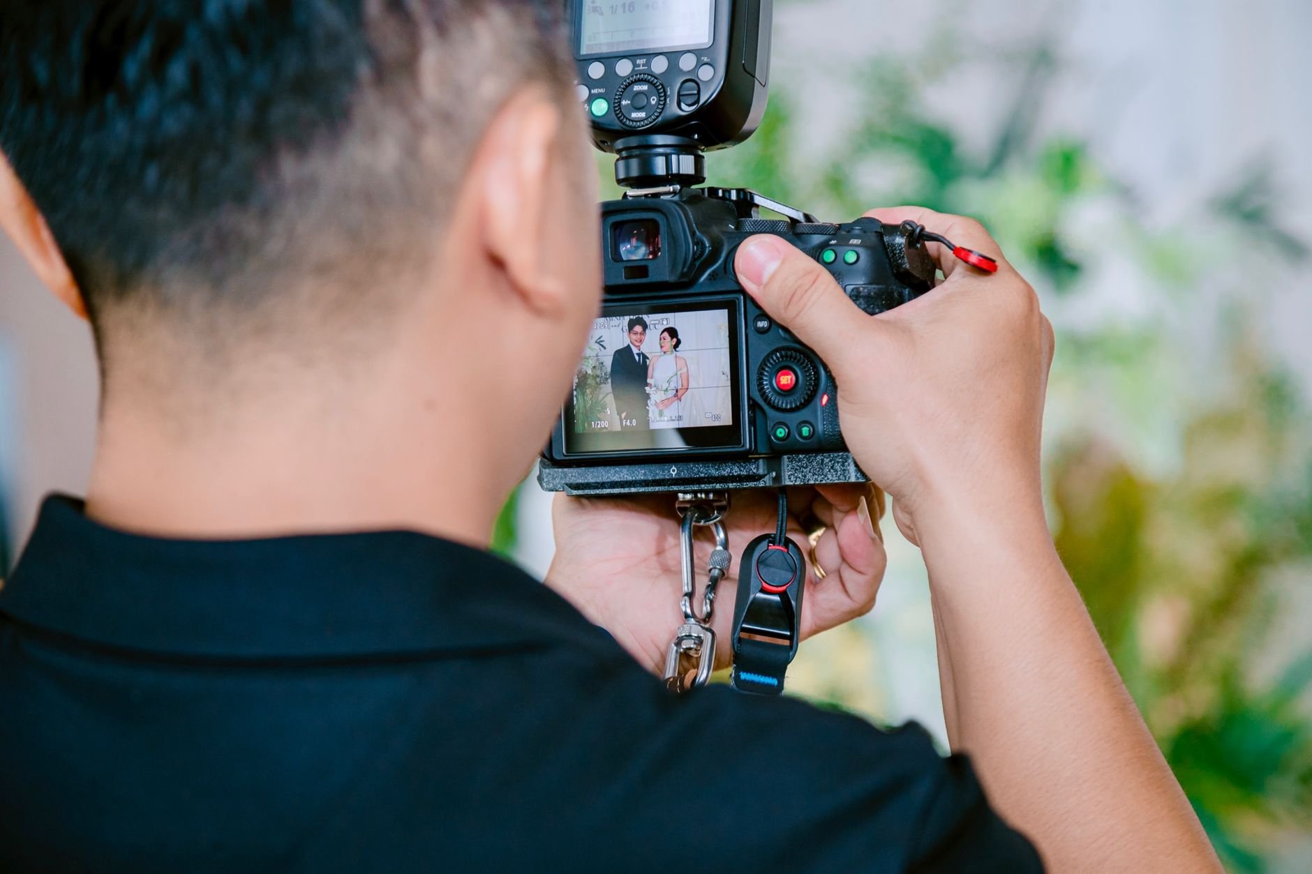 A photographer focuses on capturing a wedding couple using a digital camera during a ceremony.